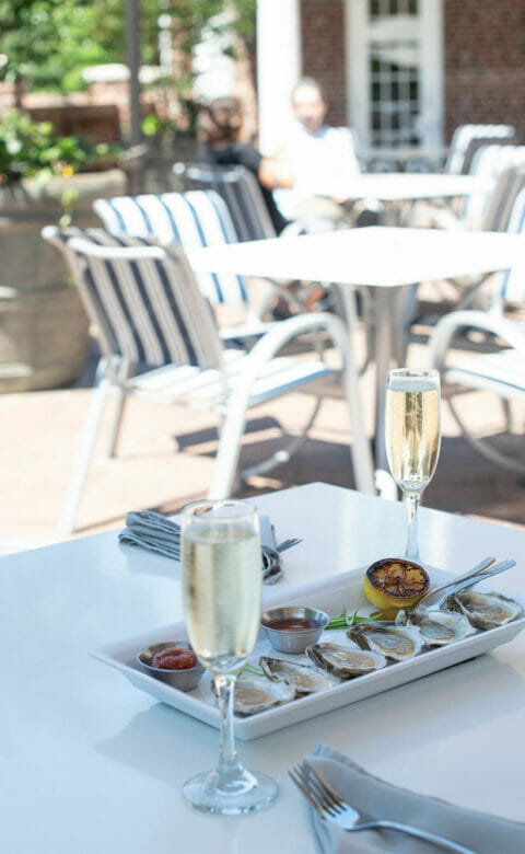 outdoor verandah dining table with two glasses of champagne and plate of six oysters