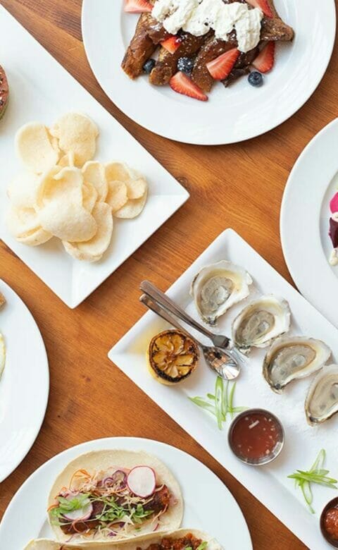 oysters, salad, french toast, eggs and sausage all on different plates