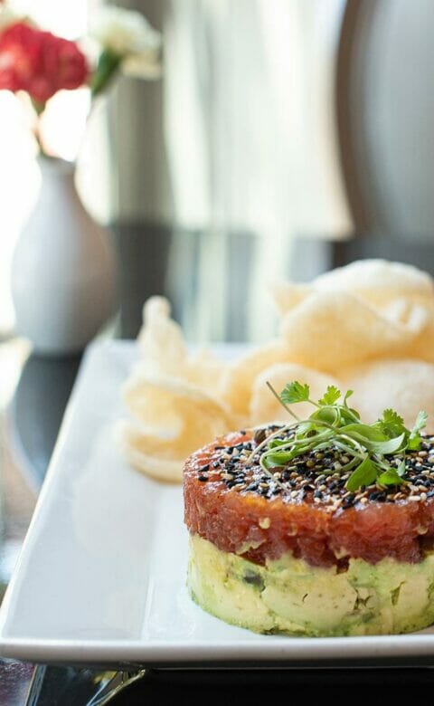 an appetizer of tuna tartare with avocado and crispy chips