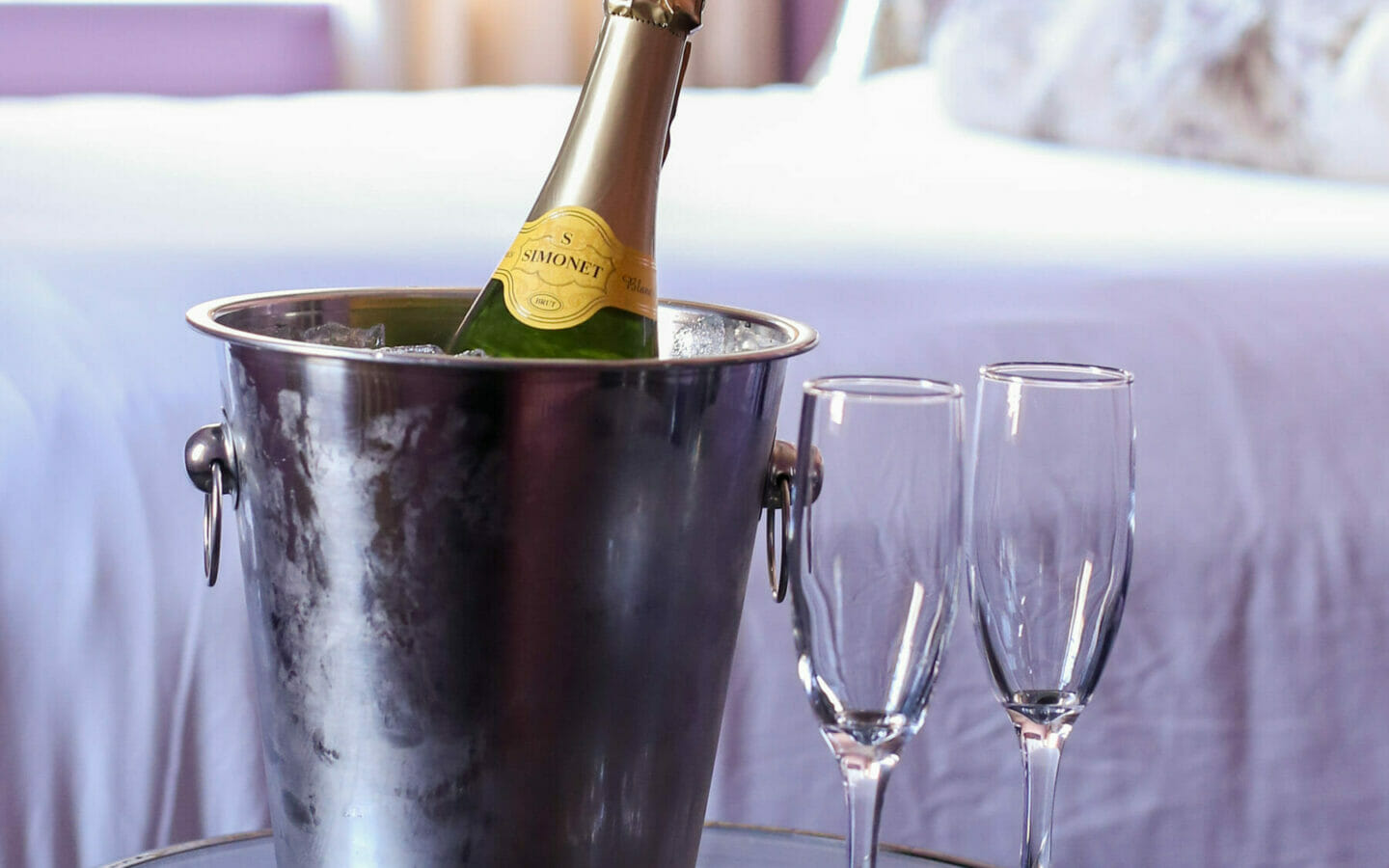 Champagne on ice with two glasses on stand in hotel room