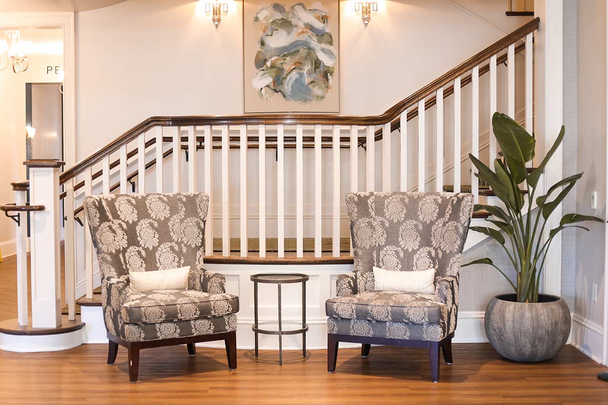 two armchairs with a floral design in front of a staircase landing