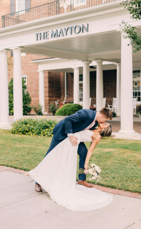 bride and groom kissing in front of the mayton