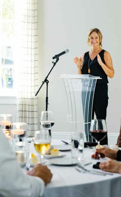 a woman on a dais speaking to a room of people